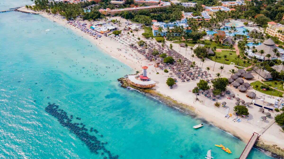 Vista aérea de Dominicus Bayahíbe, República Dominicana, con playa de aguas cristalinas, el faro costero y desarrollos turísticos integrados, en una zona clave para la inversión inmobiliaria de largo plazo.