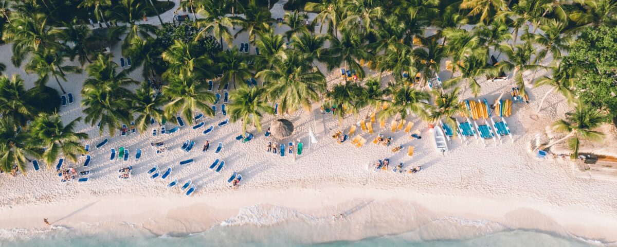 Vista aérea de la playa de Dominicus Bayahíbe con palmeras, arena blanca, reposeras y mar turquesa en la costa sureste de República Dominicana.