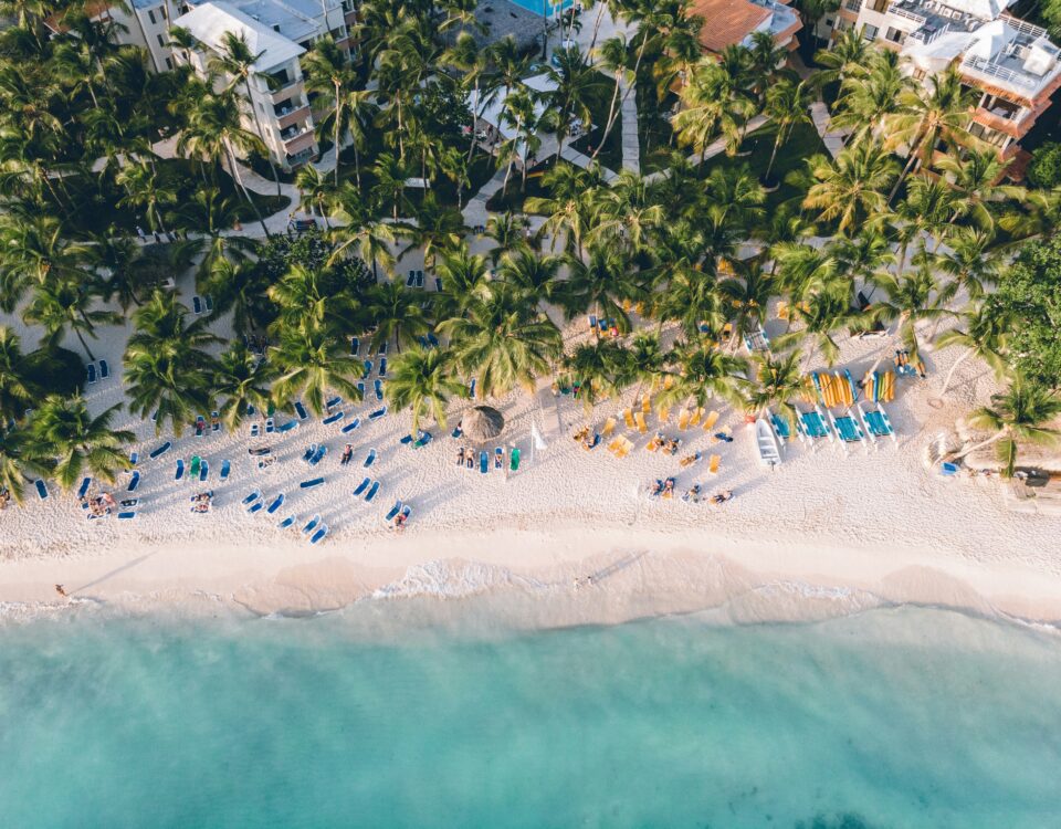 Vista aérea de la playa de Dominicus Bayahíbe con palmeras, arena blanca, reposeras y mar turquesa en la costa sureste de República Dominicana.